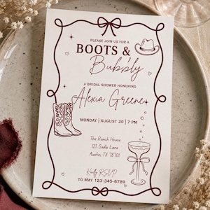 Puede incluir: Una tarjeta de invitación rectangular blanca con texto y dibujos de líneas en rojo oscuro. El texto dice Boots & Bubbly, A Bridal Shower Honoring Alexia Greene, Monday August 20 7 PM, The Ranch House 123 Sadle Lane Austin TX 78701, Kindly RSVP to May 123-345-6789.