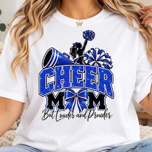 Könnte beinhalten: Ein weißes T-Shirt mit einem Grafikdesign, das den Text "CHEER MOM" in blauen Glitzerbuchstaben zeigt. Das Design umfasst ein blaues Megafon, einen blauen Pompon, eine blaue Schleife und die Silhouette einer Cheerleaderin. Darunter steht der Text "But Louder and Prouder" in schwarzer Schrift.