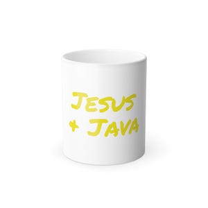 Puede incluir: Taza de cerámica blanca con la inscripción amarilla "JESUS + JAVA" en un estilo manuscrito. La taza es cilíndrica y tiene un diseño sencillo y limpio, adecuada para bebidas calientes.