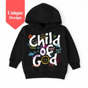 Könnte beinhalten: Schwarzer Kapuzenpullover mit dem Schriftzug "Child of God" in Weiß, mit farbenfrohen Akzenten und Grafiken. Das Design umfasst ein Smiley, Herzen, Sterne und andere inspirierende Wörter. Ein rotes Etikett in der oberen linken Ecke lautet "Unique Design".