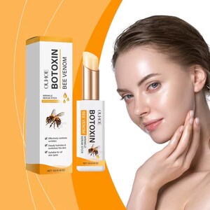 May include: A white and gold Ouhoe Botoxin Bee Venom wrinkle serum stick in a matching rectangular box. The packaging features a bee illustration, the product name, and the net weight of 5g/0.18 oz. The stick has a twist-up mechanism.