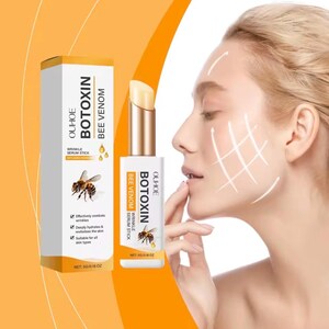 May include: A white and gold OUHOE BOTOXIN BEE VENOM wrinkle serum stick with a bee graphic on the packaging. The box and stick both display the text OUHOE BOTOXIN BEE VENOM and NET: 5G/0.18 OZ. The product is shown next to a profile of a face.