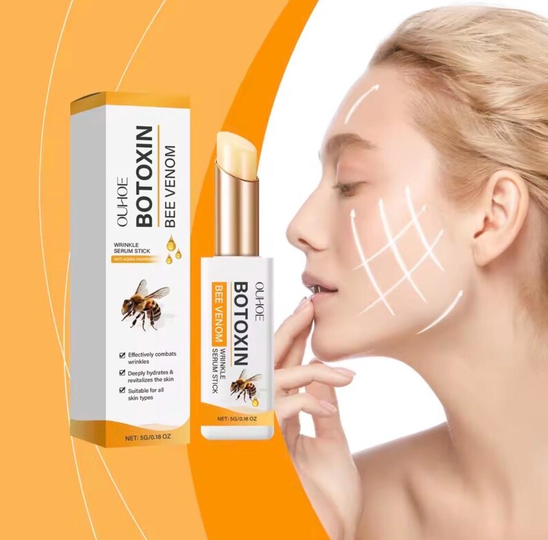 May include: A white and gold OUHOE BOTOXIN BEE VENOM wrinkle serum stick with a bee graphic on the packaging. The box and stick both display the text OUHOE BOTOXIN BEE VENOM and NET: 5G/0.18 OZ. The product is shown next to a profile of a face.