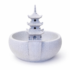 Peut inclure: Fontaine de pagode en pierre grise avec une structure à trois niveaux et un sommet pointu, placée dans un bol rond et texturé. Une pièce décorative pour jardin ou intérieur.