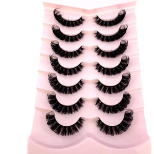 May include: Six pairs of black false eyelashes displayed on a pink plastic holder. The lashes are full and curved. The holder is designed with multiple tiers to keep each pair of lashes separate and organised.