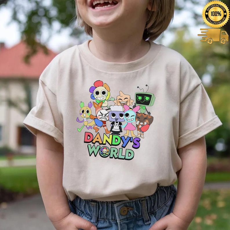 Może przedstawiać: Beżowa koszulka z kolorową grafiką postaci z kresk&oacute;wek i napisem "DANDY'S WORLD" w wielokolorowej czcionce. Projekt zawiera r&oacute;żne fantazyjne stworzenia i zabawną estetykę.