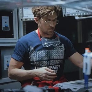 Puede incluir: Una camiseta de manga corta azul marino con un estampado gráfico blanco de la tabla periódica de los elementos en la parte delantera, con el texto "I WEAR THIS SHIRT PERIODICALLY" impreso en letras mayúsculas blancas bajo el diseño.