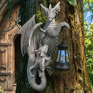 May include: A detailed gray dragon sculpture with outstretched wings and a smaller dragon figure. The sculpture is mounted on a tree trunk and holds a black lantern with blue-tinted glass. The background includes a wooden door and lush greenery.