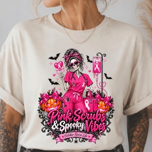 May include: A beige t-shirt featuring a graphic of a skeleton nurse in pink scrubs, holding a heart-shaped lollipop and a medical bag. The design includes pumpkins, bats, an IV drip, and the text Pink Scrubs & Spooky Vibes October Nurse Life.