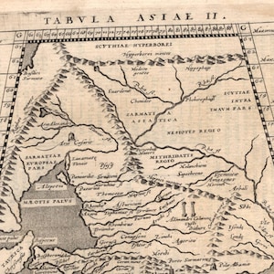 May include: Antique map titled "TABVLA ASIAE II." featuring detailed geographical elements. The map, printed on aged paper, includes text in Latin and depicts regions with rivers, mountains, and coastal areas. The map has a grid for coordinates.