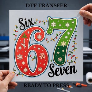 May include: A DTF transfer sheet featuring the text "DTF TRANSFER" at the top and "READY TO PRESS" at the bottom. The central graphic displays the number 67 in large red and green digits decorated with white snowflakes and string lights.