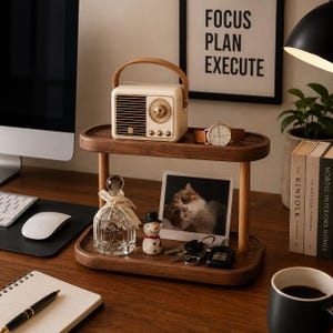 May include: A two-tiered wooden display shelf featuring a cream-coloured vintage-style radio on the top shelf. The bottom shelf holds a clear glass bottle with a ribbon, a small snowman figurine, a cat photograph, and a set of metal keys.