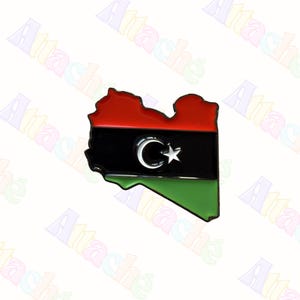 May include: A Libya-shaped pin displaying the Libyan flag. The pin has a red upper section, a black central band with a crescent and star, and a green lower section. The pin is likely made of metal.