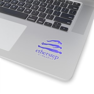 May include: A sticker with the text "etherstep" in blue, along with Japanese characters, and a graphic of three figures. The sticker is on a silver laptop.