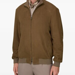 Peut inclure: Veste de bombardier en daim marron avec fermeture &eacute;clair, poignets et ourlet c&ocirc;tel&eacute;s assortis. La veste a un col montant et une doublure marron clair. Le mod&egrave;le porte une chemise et un pantalon marron clair.