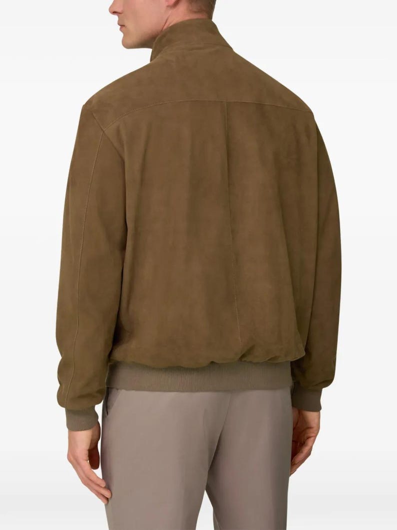 Peut inclure: Veste de bombardier en daim marron avec col montant et poignets et ourlet c&ocirc;tel&eacute;s. La veste a un design classique avec une finition lisse et mate. Le mod&egrave;le porte un pantalon assorti.