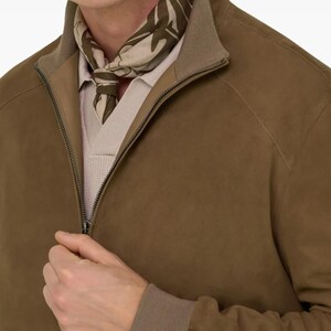 Peut inclure: Veste en daim marron avec fermeture &eacute;clair et col marron clair. La veste est associ&eacute;e &agrave; une &eacute;charpe &agrave; motifs dans les tons verts et beiges. Le mod&egrave;le porte une chemise beige clair sous la veste.