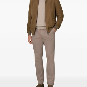 Peut inclure: Veste de bombardier en daim marron avec fermeture &eacute;clair, associ&eacute;e &agrave; un pull beige et un pantalon kaki. L'ensemble est compl&eacute;t&eacute; par des mocassins marron. Un look classique et d&eacute;contract&eacute;.