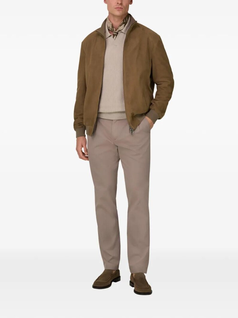 Peut inclure: Veste de bombardier en daim marron avec fermeture &eacute;clair, associ&eacute;e &agrave; un pull beige et un pantalon kaki. L'ensemble est compl&eacute;t&eacute; par des mocassins marron. Un look classique et d&eacute;contract&eacute;.