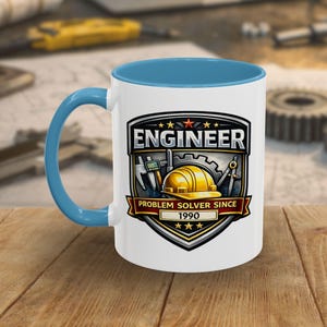May include: A white ceramic mug with a blue interior and handle. The mug features a graphic with the word "ENGINEER" and the text "PROBLEM SOLVER SINCE 1990" along with engineering tools and a hard hat.