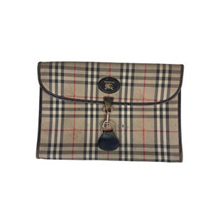 May include: A beige, black, and red check pattern clutch bag with a flap closure. The bag has a black leather trim and a small, circular emblem with text. A silver-toned clasp and a black leather fob are attached.