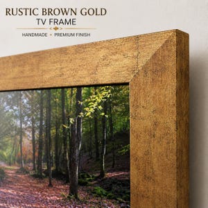 Puede incluir: Un marco de televisión de color marrón dorado rústico con un acabado texturizado. El marco rodea una pantalla que muestra un sendero forestal con árboles y hojas caídas. El texto superior dice RUSTIC BROWN GOLD TV FRAME, HANDMADE, PREMIUM FINISH.