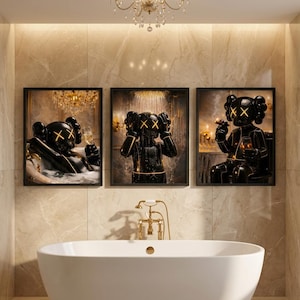 May include: Three framed wall art prints featuring a glossy black character with yellow X-shaped eyes. The left print shows the character in a bathtub with a glass, the center shows it showering, and the right shows it smoking and holding a glass.