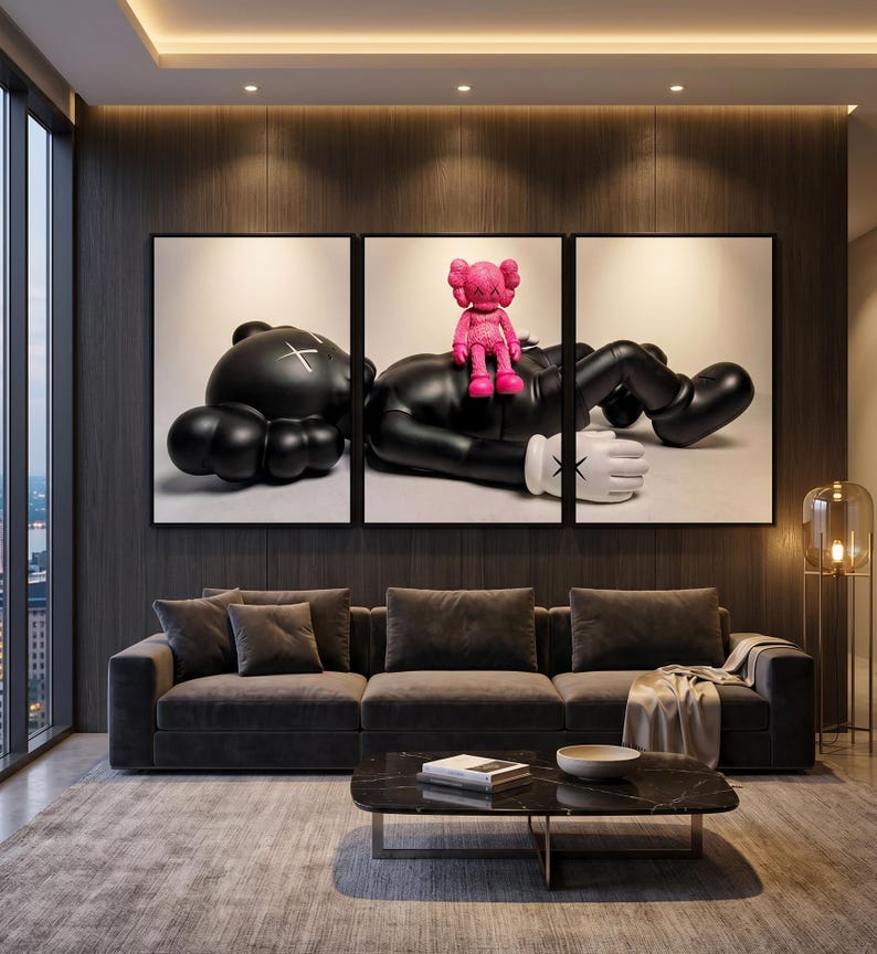 May include: A triptych wall art set featuring a large black cartoon-style figure lying down with an X-shaped mark on its head, while a smaller bright pink figure sits on its chest. The figures have white gloved hands with X-shaped markings.