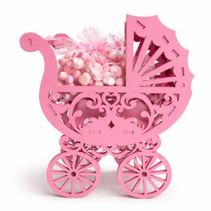 May include: A pink wooden pram filled with pink and white sweets. The pram features decorative cutouts and spoked wheels. A clear cellophane bag filled with sweets is tied with a pink ribbon.