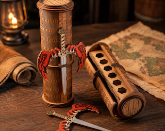 May include: Wooden pen holder with a decorative sword and red wing design. The pen holder is cylindrical and has a matching lid. A second pen holder is open, revealing hexagonal pen slots. A map and lantern are in the background.
