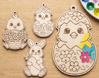 May include: Four unfinished wooden Easter ornaments: a chick with a basket of flowers, a chick hatching from an egg, a bunny holding a carrot, and a larger chick hatching from an egg. The largest ornament has some areas painted with yellow, blue, and pink.