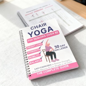 Peut inclure: Un livre à spirales intitulé "Chair Yoga for Seniors Over 60" avec une bordure rose. La couverture présente une illustration d'une personne faisant du yoga sur chaise. Le livre promet perte de poids, force, mobilité et équilibre. Un autre livre est visible en arrière-plan.