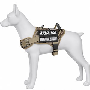 May include: A tan and brown digital camouflage dog harness on a white canine mannequin. The harness features two black rectangular patches with white text reading SERVICE DOG and EMOTIONAL SUPPORT, a black plastic buckle, and a top handle.