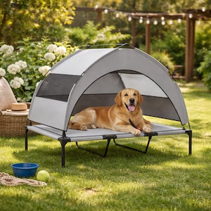 May include: A golden retriever dog rests on a gray elevated pet bed with a gray canopy. The dog bed has black legs and is placed on a grassy lawn. A blue bowl and a tennis ball are nearby.
