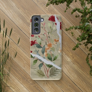 May include: A phone case with a floral design. The case features red and orange flowers, green leaves, and a white torn paper effect against a beige background. The phone case is on a wooden surface.