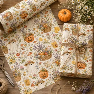 May include: Gift wrap with a repeating pattern of pumpkins, ghosts, flower baskets, and mushrooms on a cream background. A wrapped gift tied with twine and decorated with flowers is in the image, along with a roll of the same paper.