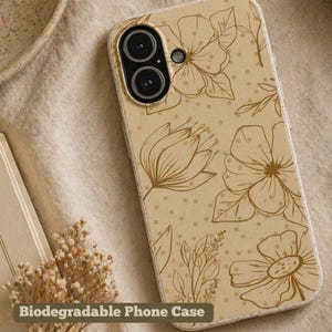 May include: A beige phone case with a floral design. The case features brown line art of flowers and leaves, with small brown dots scattered across the surface. The text "Biodegradable Phone Case" is visible at the bottom.