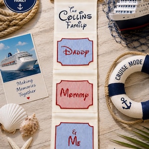 May include: Cream fabric wall organiser with the text "The Collins Family" and pockets labelled "Daddy", "Mommy", and "& Me". The organiser has a nautical theme, with a cruise ship model, seashells, and a life preserver.