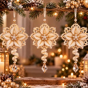 Può includere: Tre ornamenti pendenti a forma di fiori a cinque petali, realizzati in tessuto color crema con accenti in filo dorato e piccole perle bianche. Ogni ornamento presenta una coda a spirale che termina con una goccia di cristallo sfaccettato.