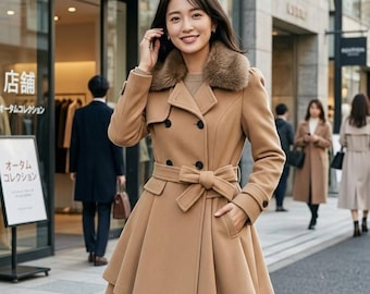 May include: A tan double-breasted coat with a faux fur collar and a belted waist. The coat has a flared skirt and black buttons. The person is standing on a city street.
