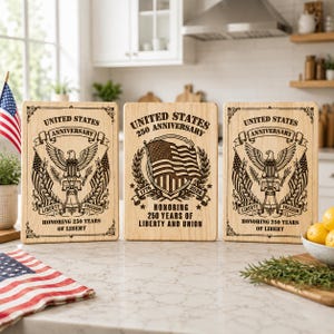 May include: Three rectangular wooden cutting boards featuring laser-engraved designs. Two boards display an eagle, a bell, and the text UNITED STATES ANNIVERSARY LIBERTY FREEDOM. The center board shows an American flag and UNITED STATES 250 ANNIVERSARY.