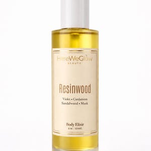 Resinwood luxury body oil for glowing skin in frosted 4oz glass bottle, long lasting woody musk perfume oil, nongreasy hydrating skin oil, HereWeGlow Beauty.