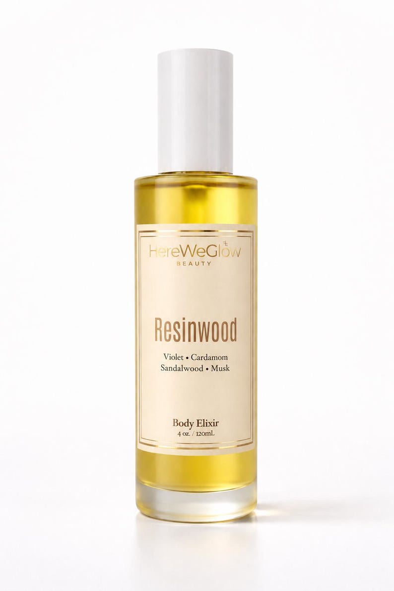 Resinwood luxury body oil for glowing skin in frosted 4oz glass bottle, long lasting woody musk perfume oil, nongreasy hydrating skin oil, HereWeGlow Beauty.