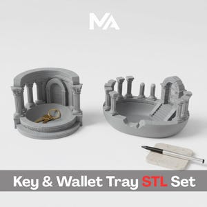 May include: Two gray, architectural-themed key and wallet trays. One tray features a domed structure with columns, holding keys. The other has a gate and stairs design. A pen rests on a small, rectangular stone. Text reads "Key & Wallet Tray STL Set."