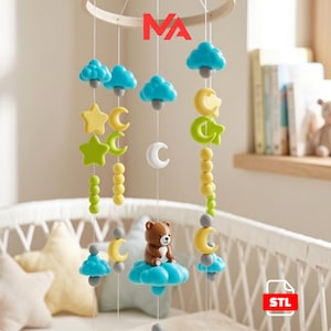 May include: A baby mobile with a wooden ring and hanging decorations. The mobile features blue clouds, yellow stars and moons, green beads, and a brown bear sitting on a blue cloud. The letters "NA" are at the top.