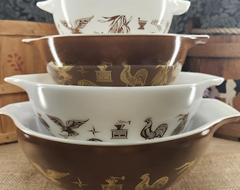 May include: A set of four nested mixing bowls with handles, alternating between white and brown glass. The bowls feature a repeating pattern of brown or gold illustrations including eagles, roosters, coffee grinders, and wheat stalks.