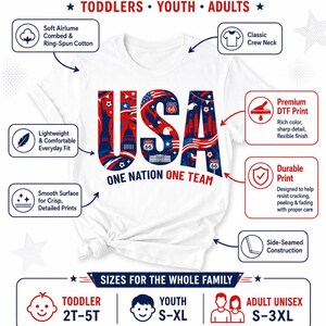 May include: A white crew neck t-shirt featuring a large graphic of the letters USA filled with patriotic imagery including the Statue of Liberty, bald eagles, and Route 66 signs. The text ONE NATION ONE TEAM is printed below in red and blue.