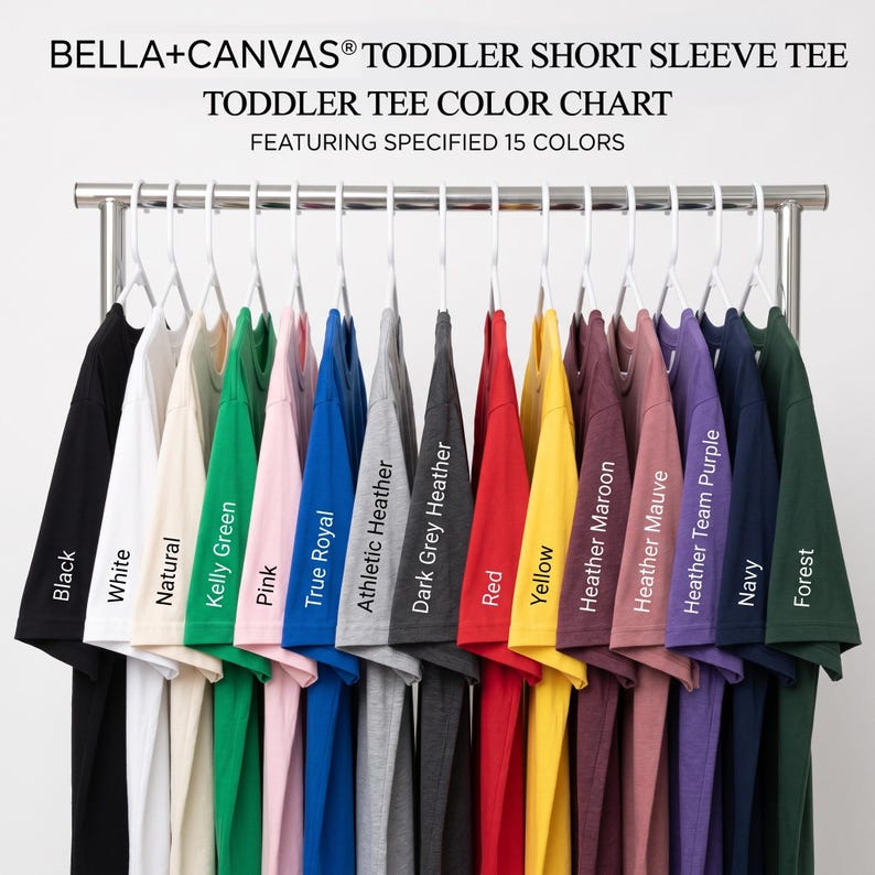 May include: A Bella+Canvas toddler short sleeve tee color chart featuring 15 shirts on white hangers. Colors include black, white, natural, kelly green, pink, true royal, athletic heather, dark grey heather, red, yellow, heather maroon, heather mauve, heather team purple, navy, and forest.