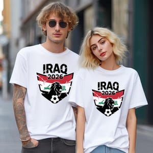 May include: Two people wearing white t-shirts. Each shirt has a graphic design with the word "IRAQ" above "2026", and a lion with a football. The shirts are short-sleeved.