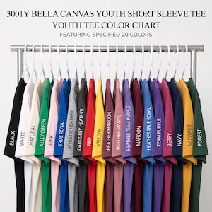 May include: A color chart for 3001Y Bella Canvas youth short sleeve tees, displaying 20 shirts on white hangers. Colors include black, white, natural, kelly green, pink, true royal, athletic heather, dark grey heather, red, yellow, maroon, mauve, purple, berry, navy, mustard, and forest.